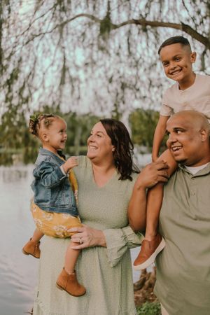 Casual family photo session with everyone sharing laughs and hugs outdoors.