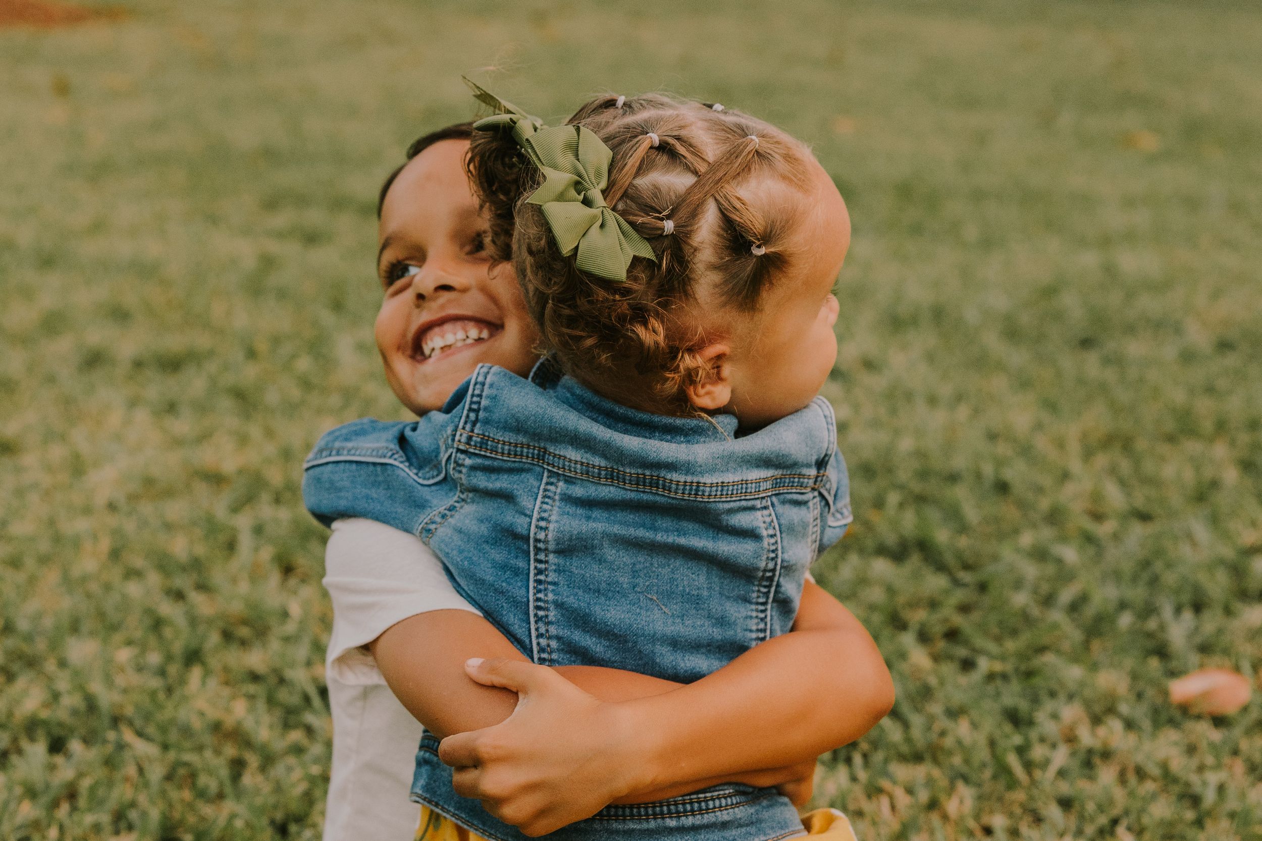 Candid moments of family members hugging and playing together in a park.