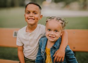 Family members sitting close together on a park bench during golden hour.