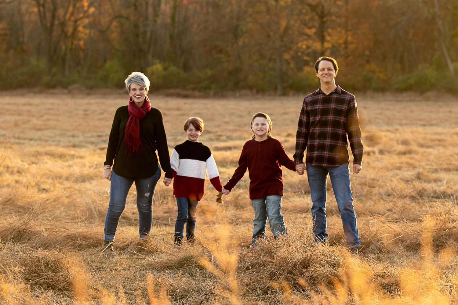 Silhouettes of a family walking together at sunset in a grassy field.