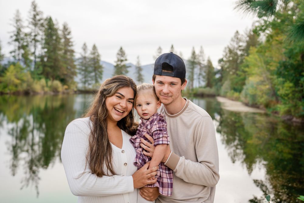 family portrait of parents with young girl by the pond