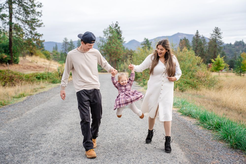parents swing toddler as they walk portrait at Pacifica in Southern Oregon