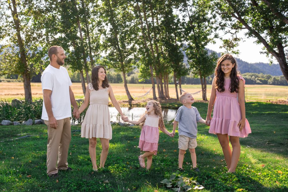 family of 5 laughs together while walking by the pond in a family portrait