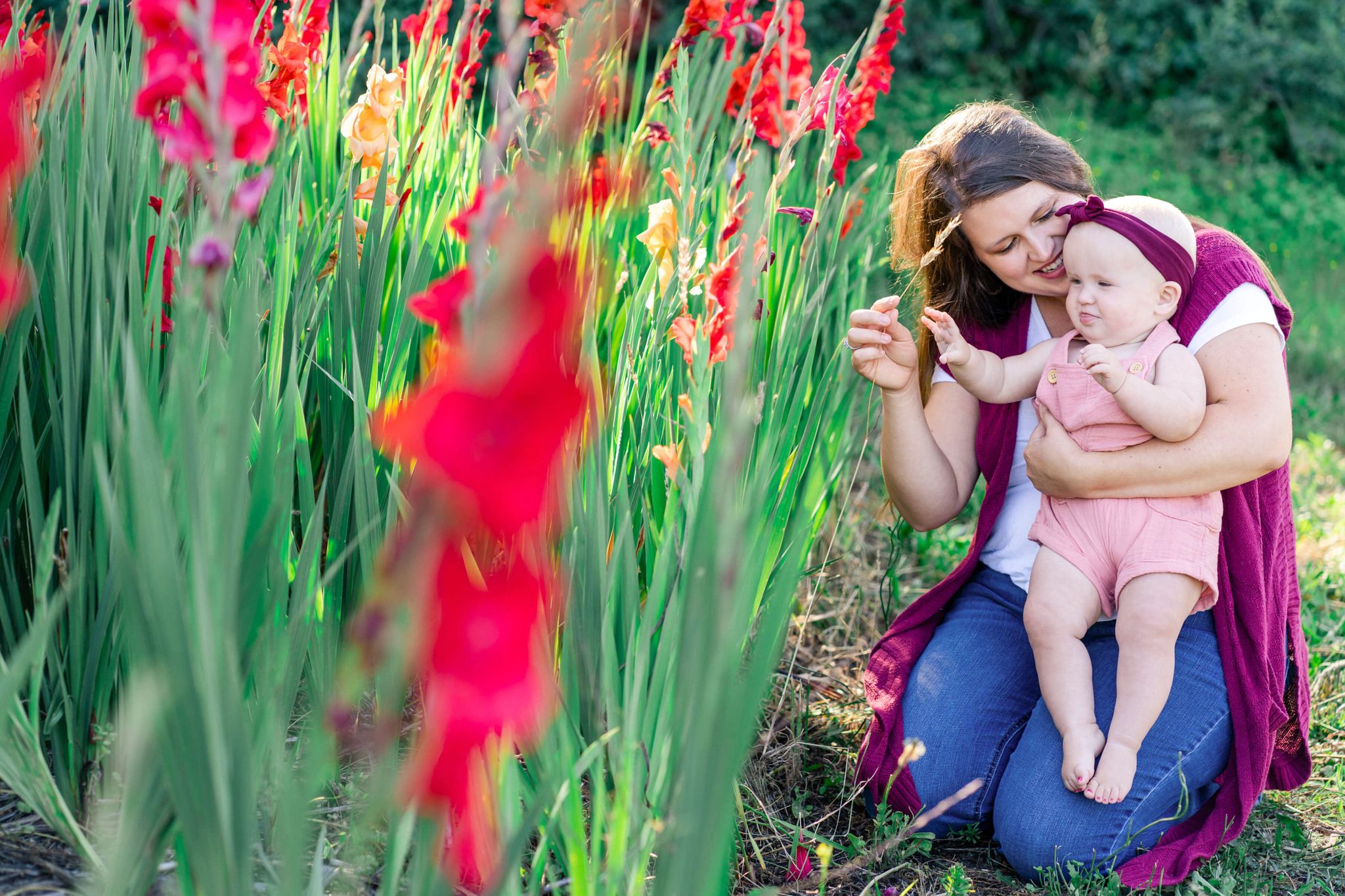 Portrait of mom and baby girl as they play by red flowers in a field