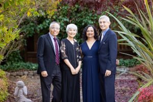 Four adults posing together in an autumn garden, dressed elegantly in navy and black formal attire.