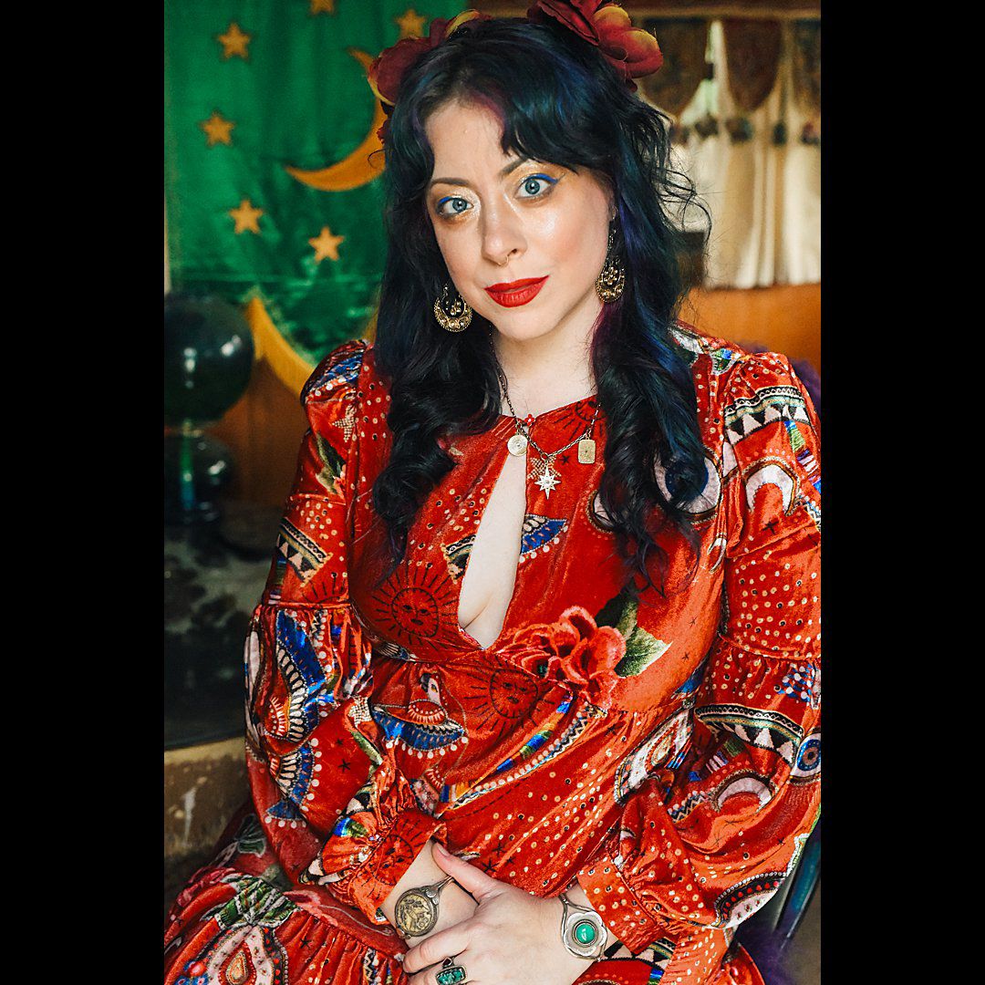 Woman in vibrant red patterned dress posing against festive green background.