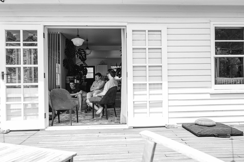 Black and white image of guests relaxing on a white cottage porch.
