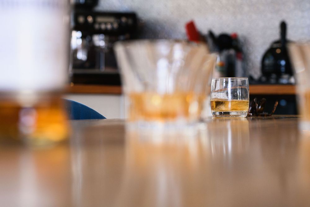 A close-up shot of cocktail glasses on a wooden bar counter with blurred background.