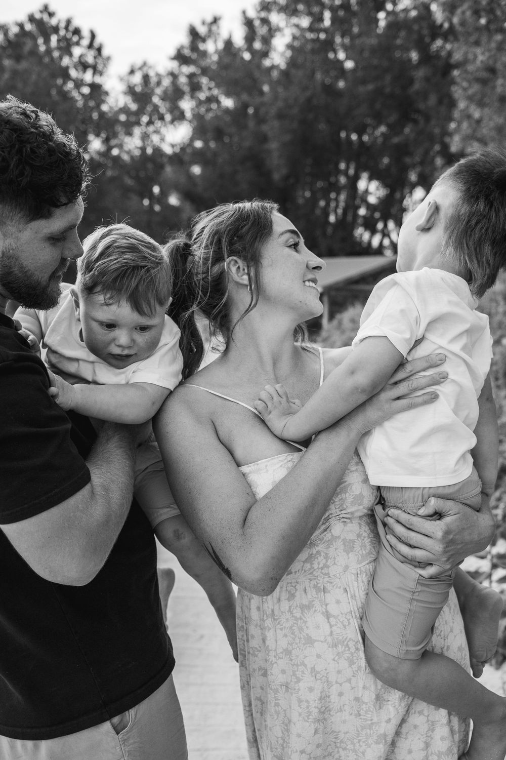 A sequence of black and white photos showing intimate family moments with parents kissing their young child.