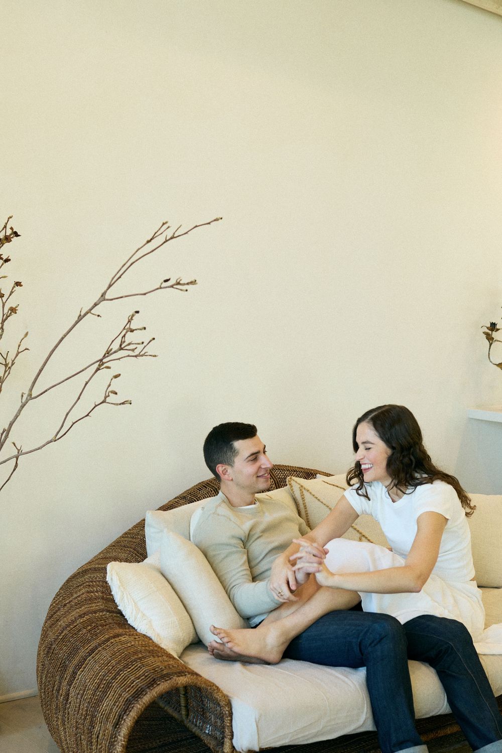 A couple sharing a tender moment while relaxing together on a woven rattan sofa with white cushions.