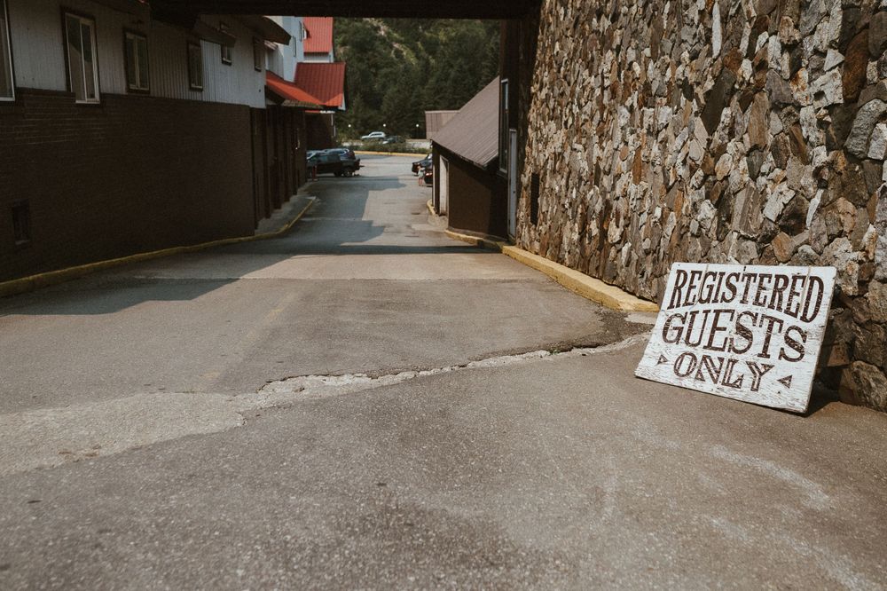A narrow road with a 'Registered Guests Only' sign against a stone wall.