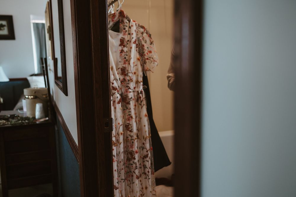 Floral pattern dress hanging in doorway with soft natural lighting.