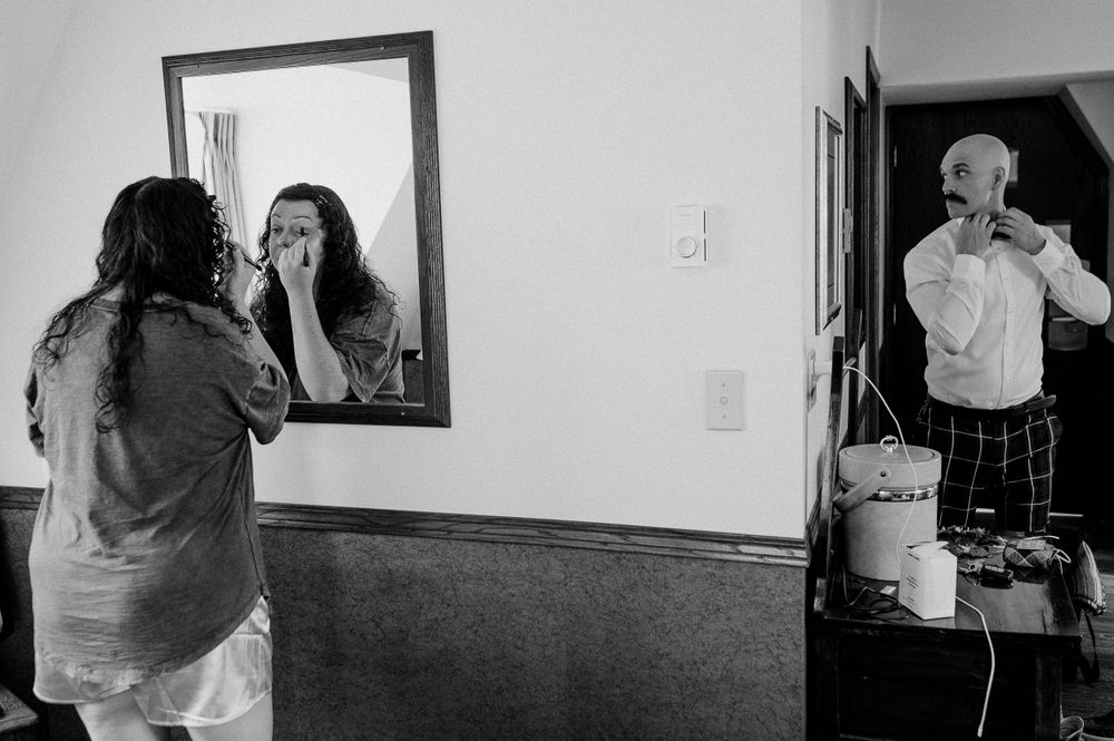 Black and white image of getting ready scene with bathroom mirror reflections.