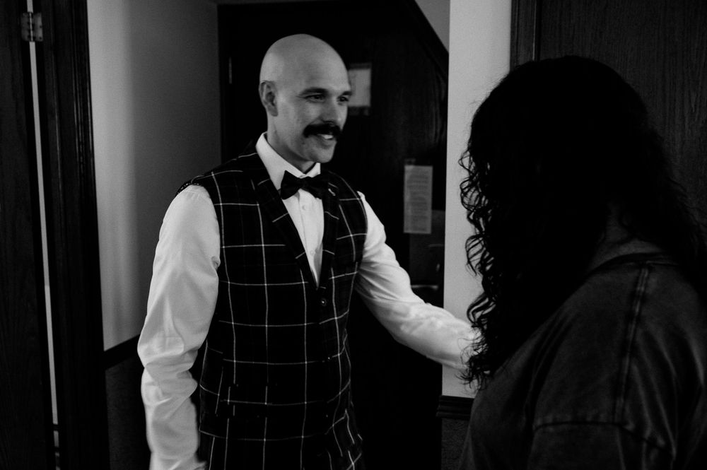 Wedding preparation scene in formal attire with checkered vest.