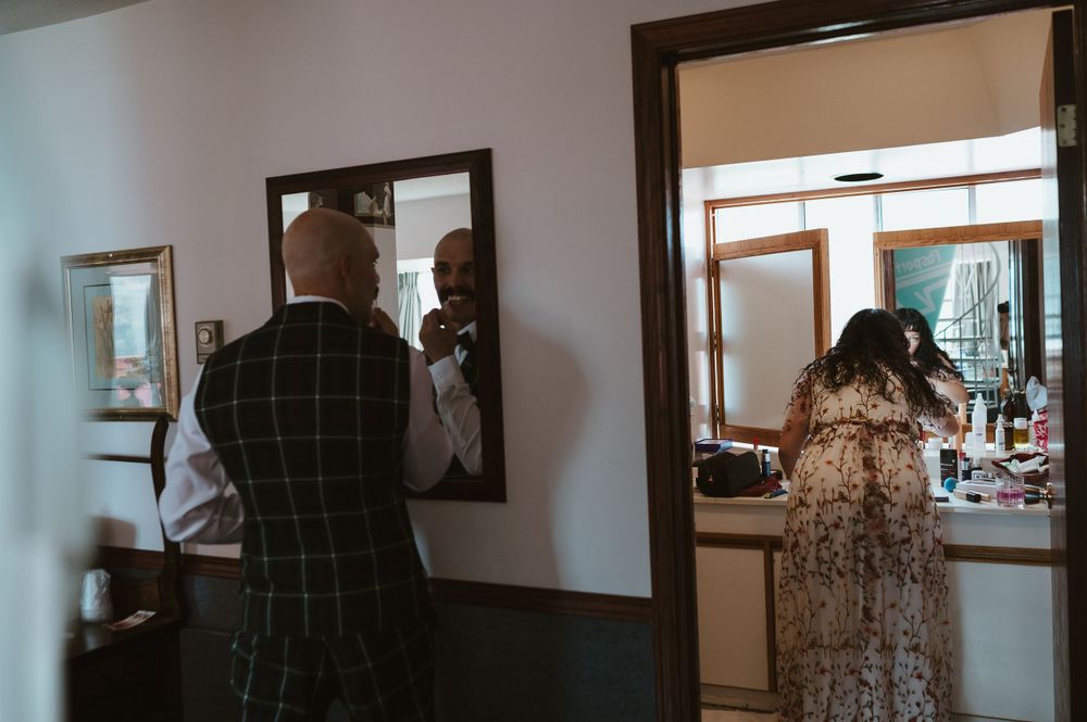 Wedding preparation scene with multiple mirrors and formal attire.