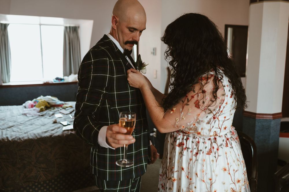Intimate moment between couple adjusting formal attire before celebration.