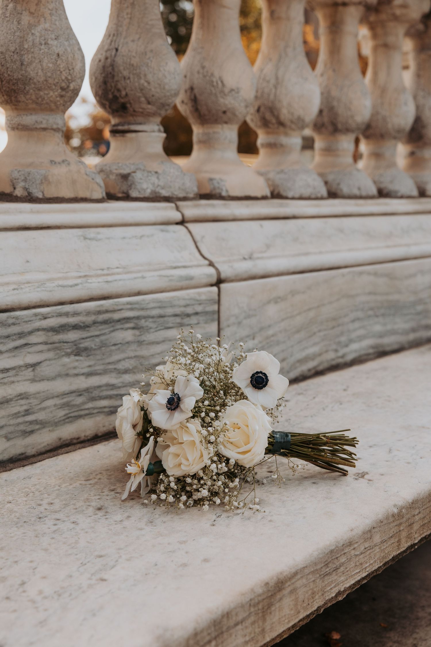 Wedding rings displayed on a pink coneflower surrounded by daisies and delicate floral arrangements in muted tones.