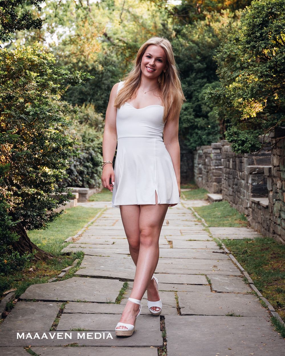 Portrait session on a stone pathway surrounded by lush green foliage and trees.