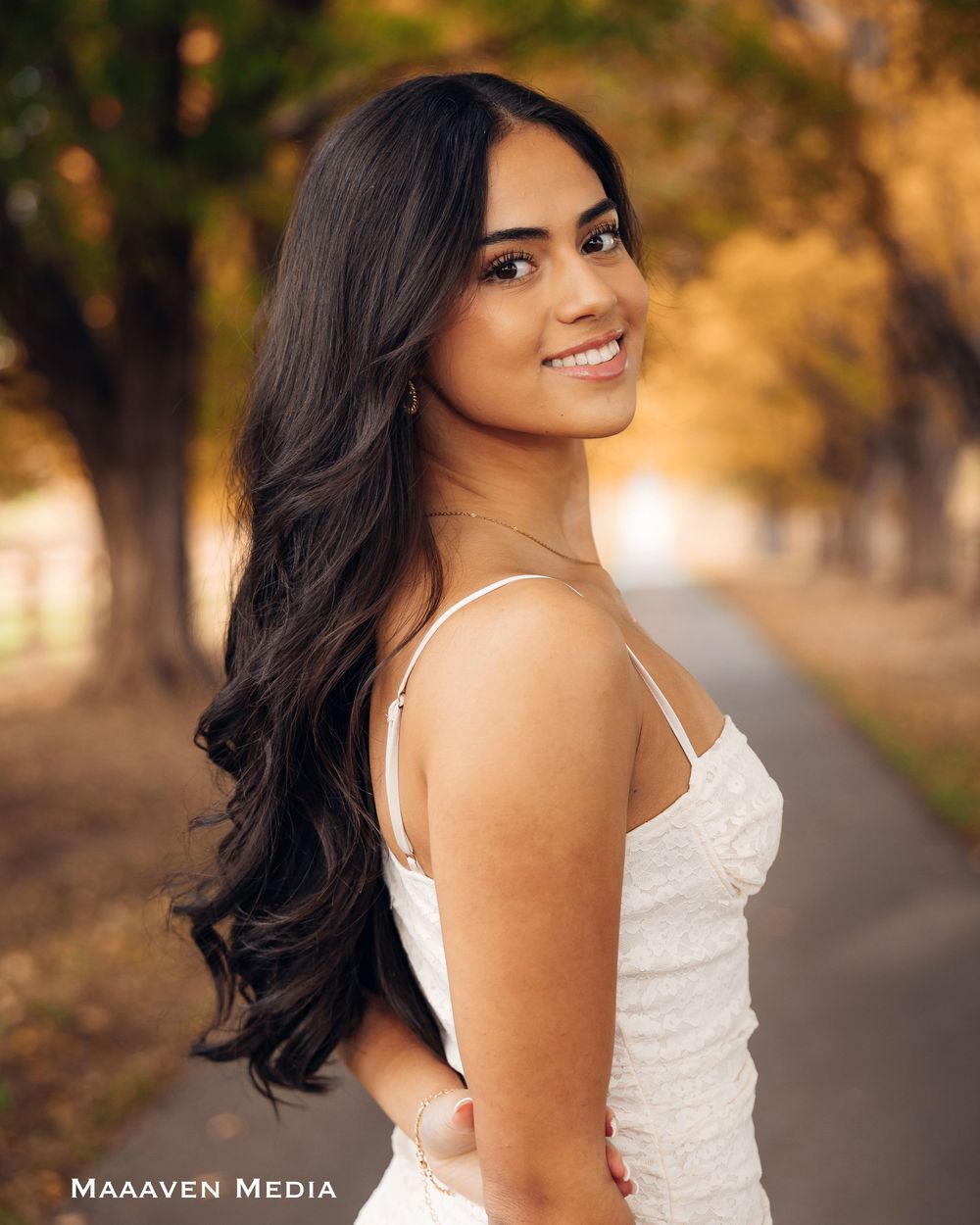 Portrait session in a park during golden hour with a white dress and long dark hair creating a dreamy atmosphere.