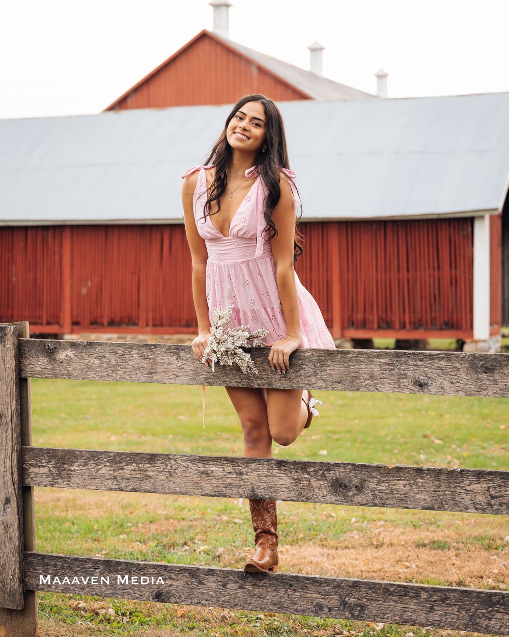 A rustic barn scene with a wooden fence and grassy field during a sunny day.