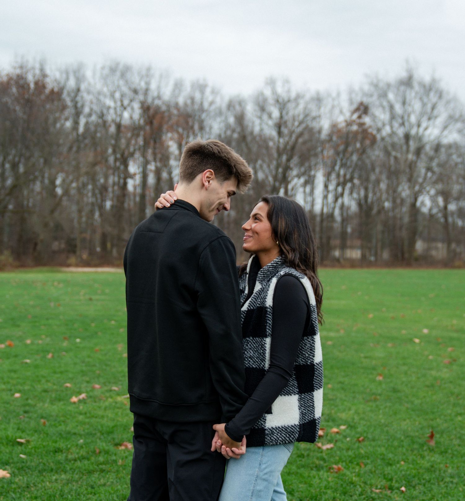Couple in casual winter wear embracing in an open field.