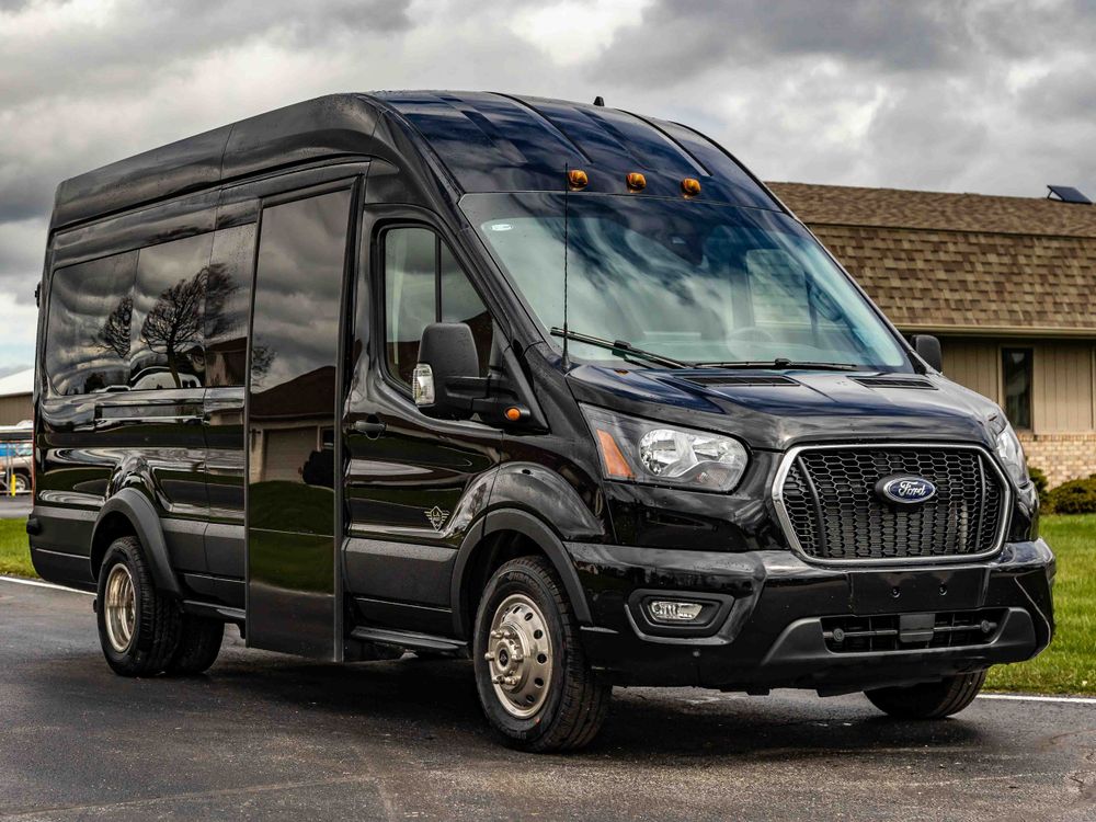Modern black Ford Transit passenger van with custom exterior trim and tinted windows.