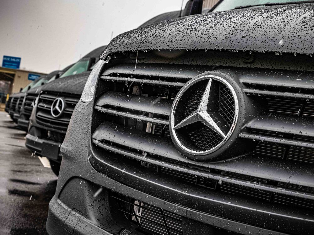Close-up of a wet Mercedes-Benz grille and logo with water droplets.