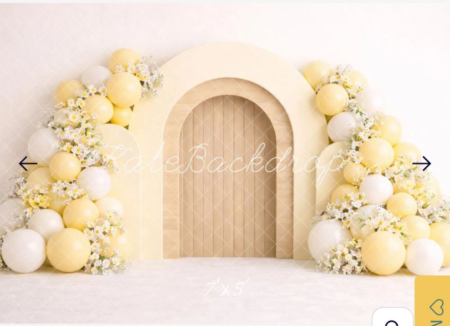 Yellow and white balloon arch with floral accents framing a wooden arched door on a white backdrop.