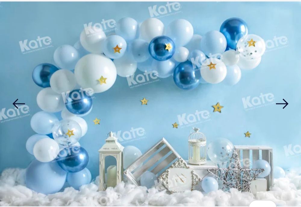 Blue and white balloon arch with lanterns and winter decorations on snowy backdrop.