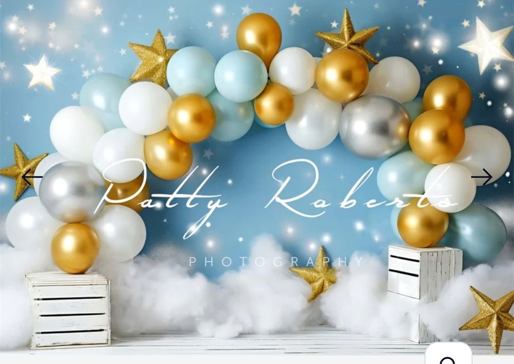 Party backdrop with gold and white balloon arch, stars and white boxes on cloudy background.