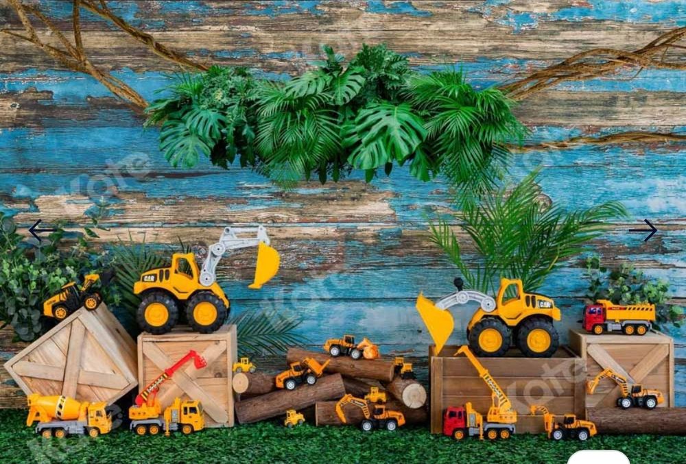 Construction themed party backdrop with toy trucks and tents against distressed blue wood.
