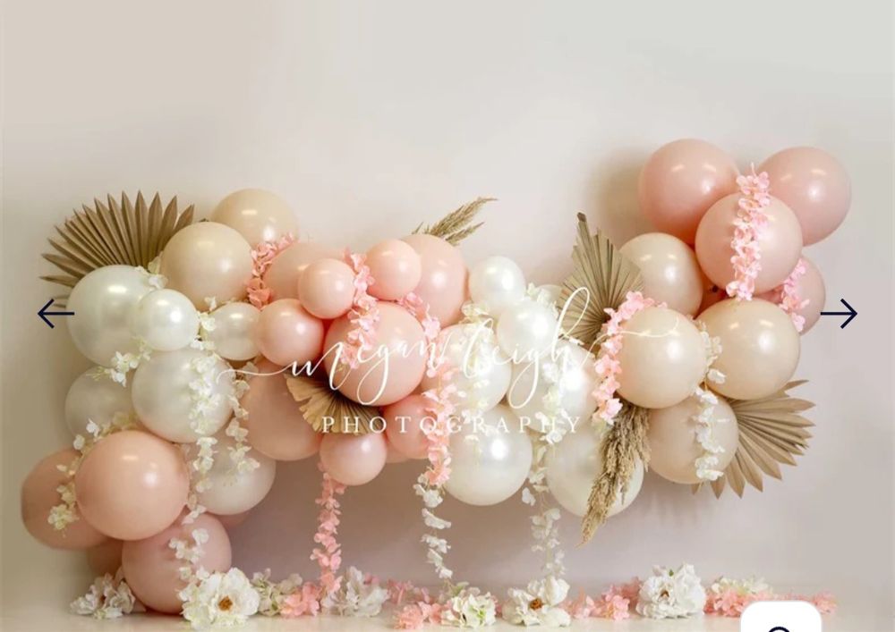 Elegant balloon garland with pink and white balloons, dried palm leaves, and floral arrangements.