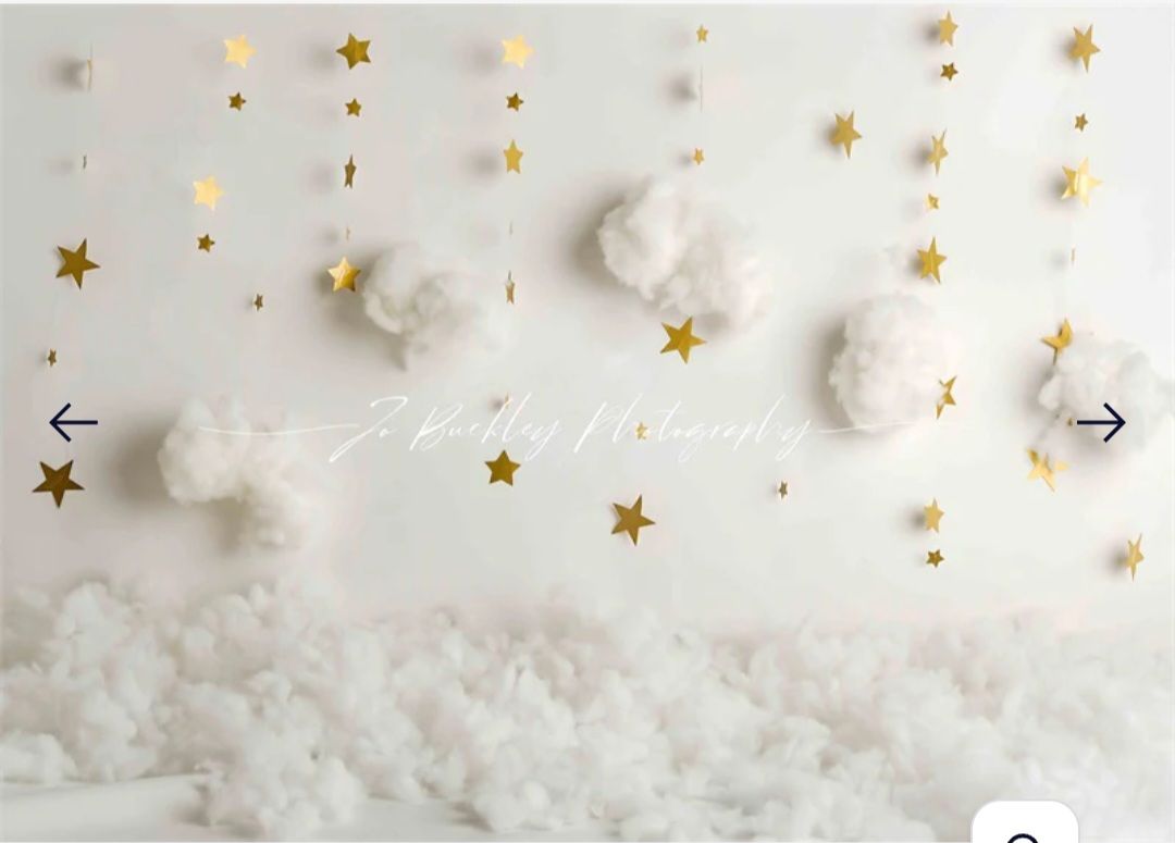 Whimsical white and gold star backdrop with cotton cloud decorations.