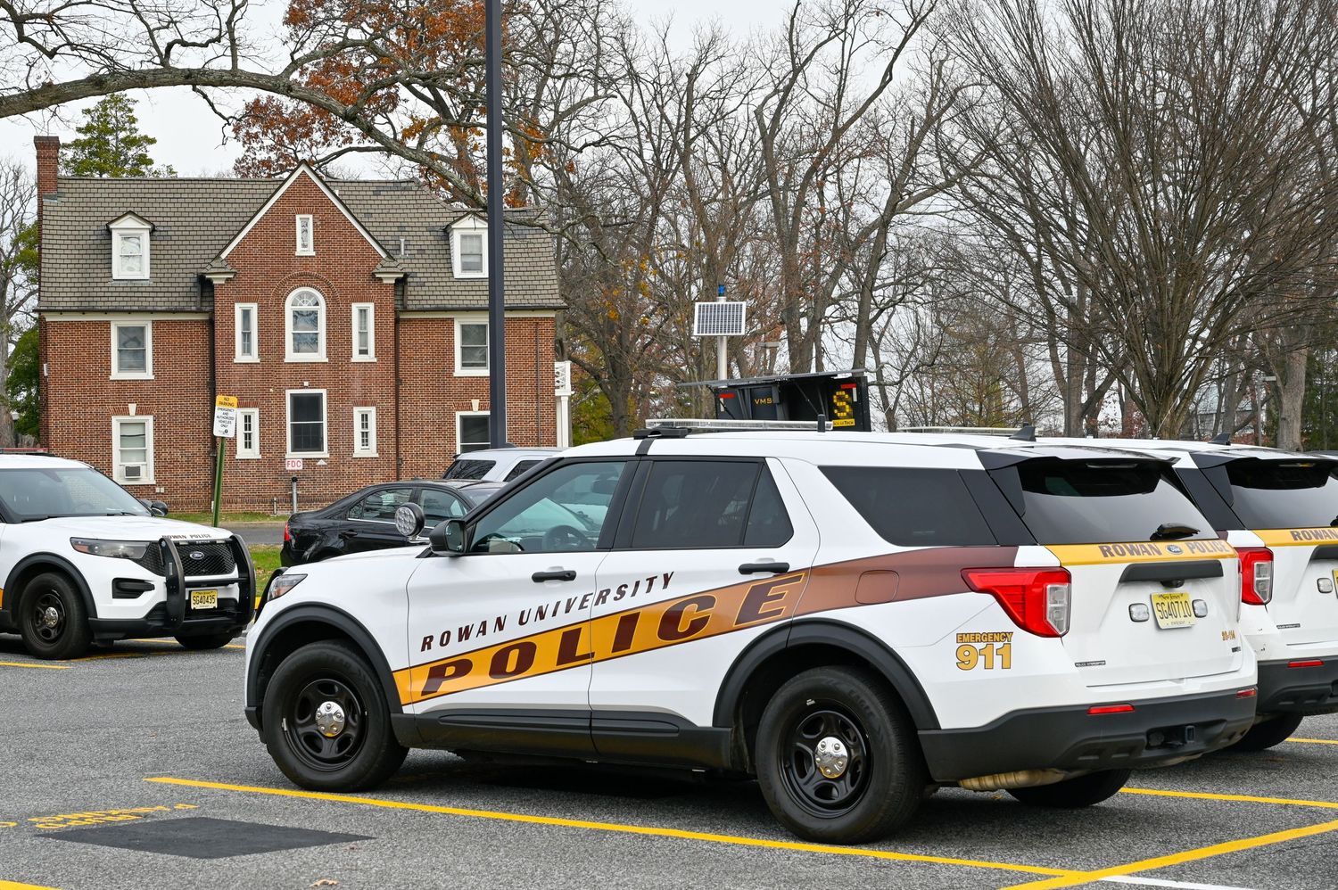 A Rowan University Public Safety police vehicle parked in front of red brick buildings.