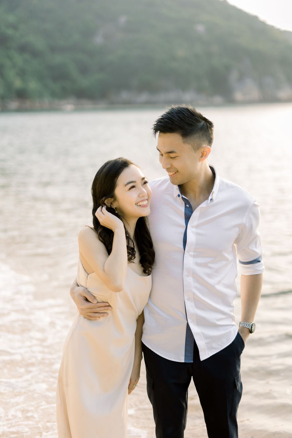 A couple shares intimate moments on a scenic beach during their engagement photo session.