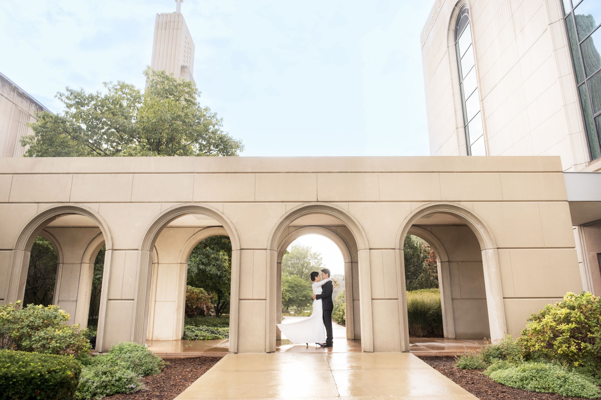 Stone archway colonnade extends along a beige building exterior, surrounded by lush greenery.
