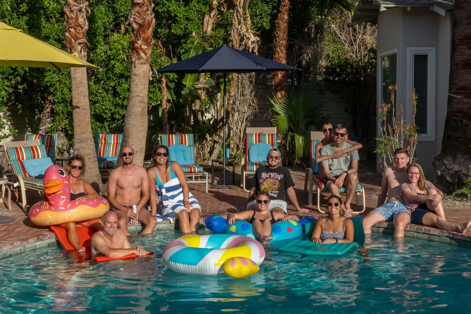 People enjoying a summer pool party with colorful floats and pool toys.