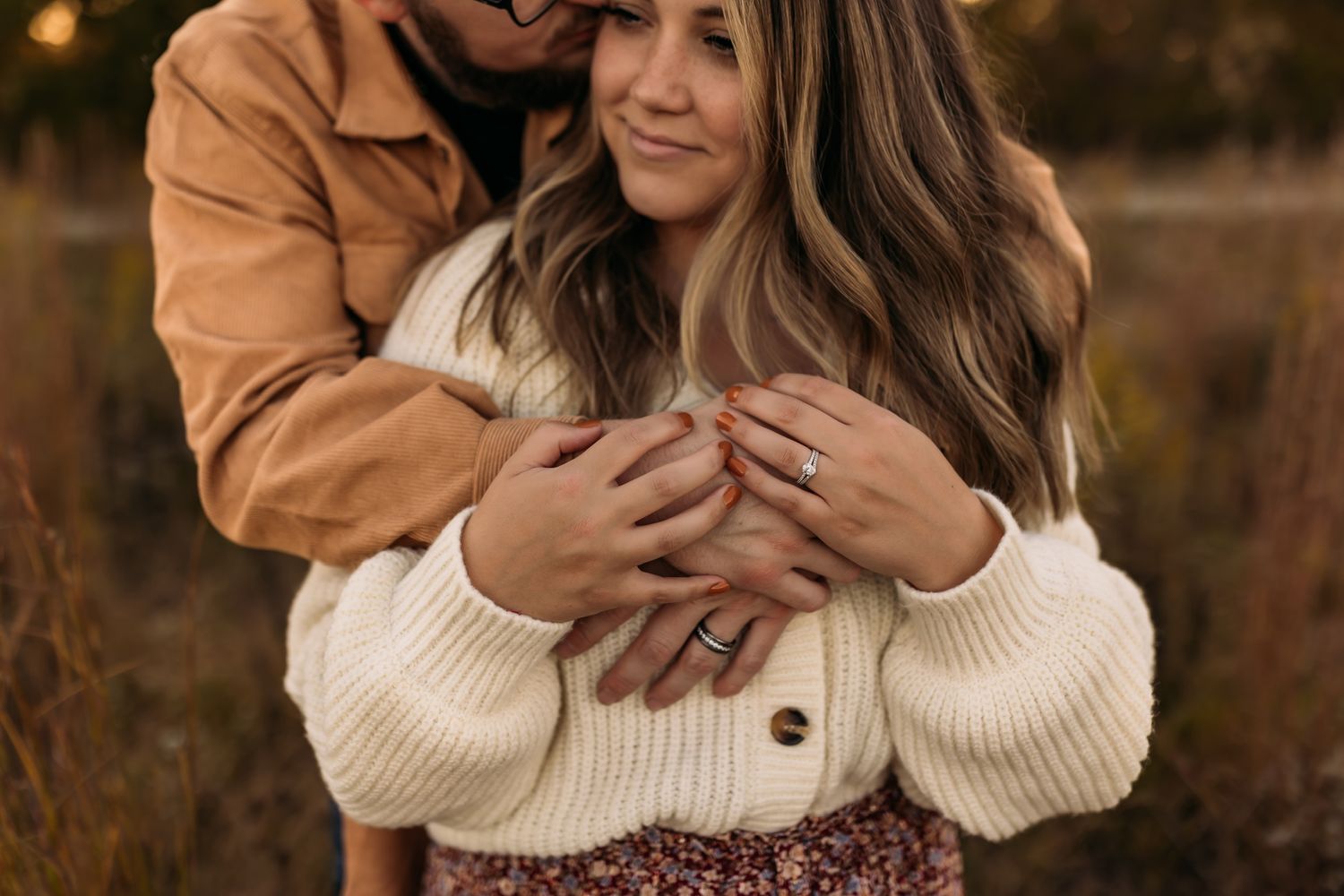 A romantic couple embracing in cozy sweaters during a sunset photoshoot.