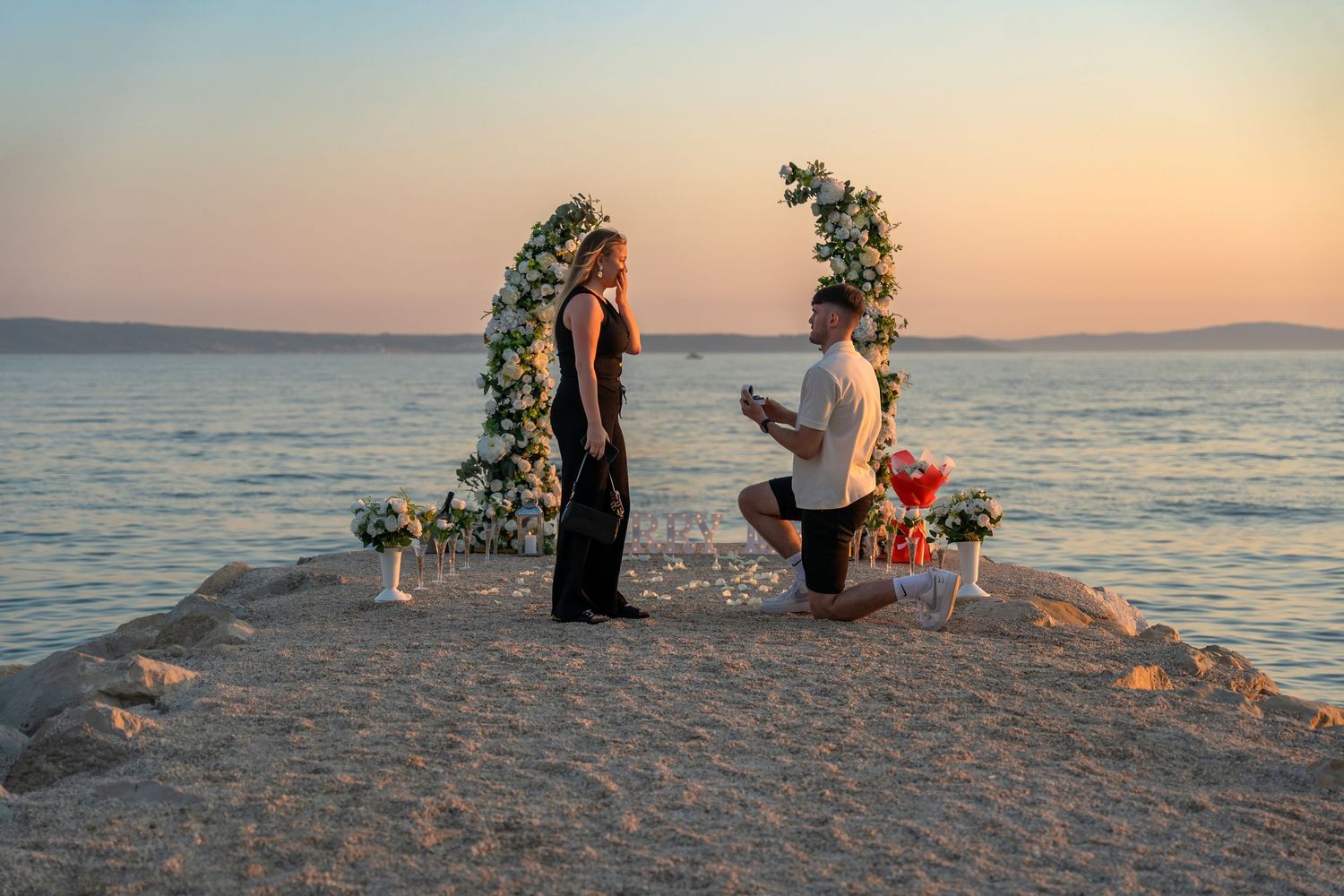 Proposal at the beach with sunset in Split Podstrana Croatia with flower arch