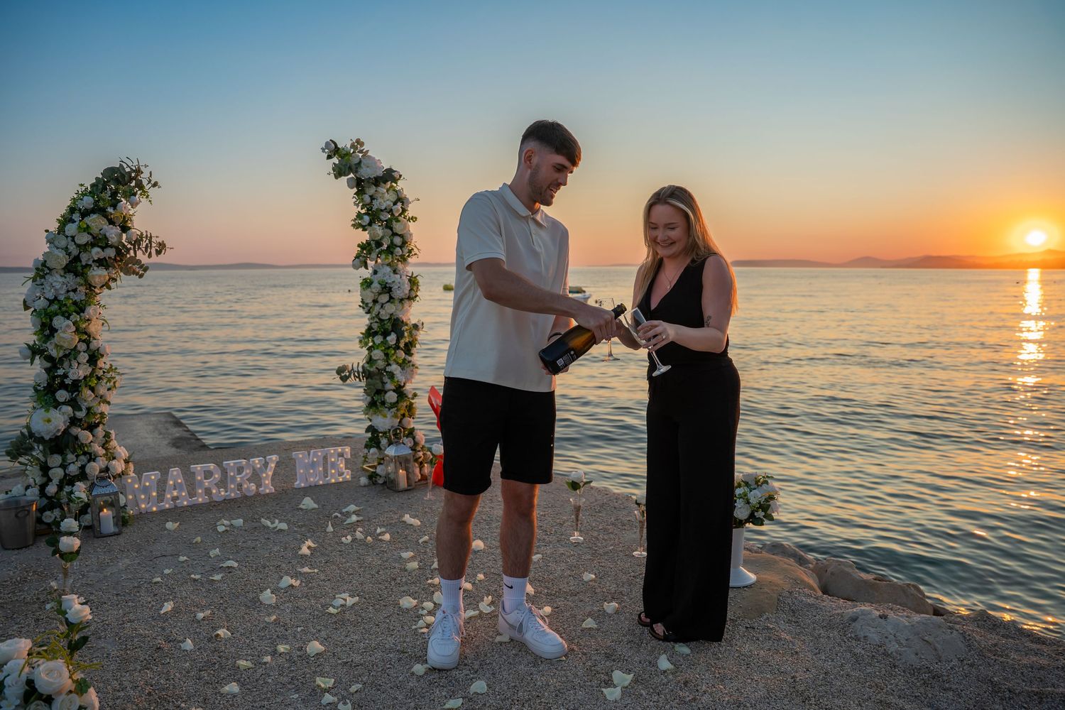 Proposal at the beach with sunset in Split Podstrana Croatia with flower arch