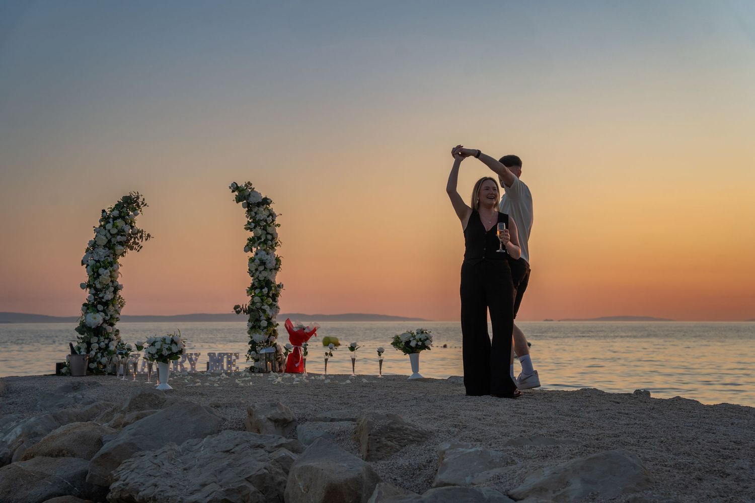 Proposal at the beach with sunset in Split Podstrana Croatia with flower arch