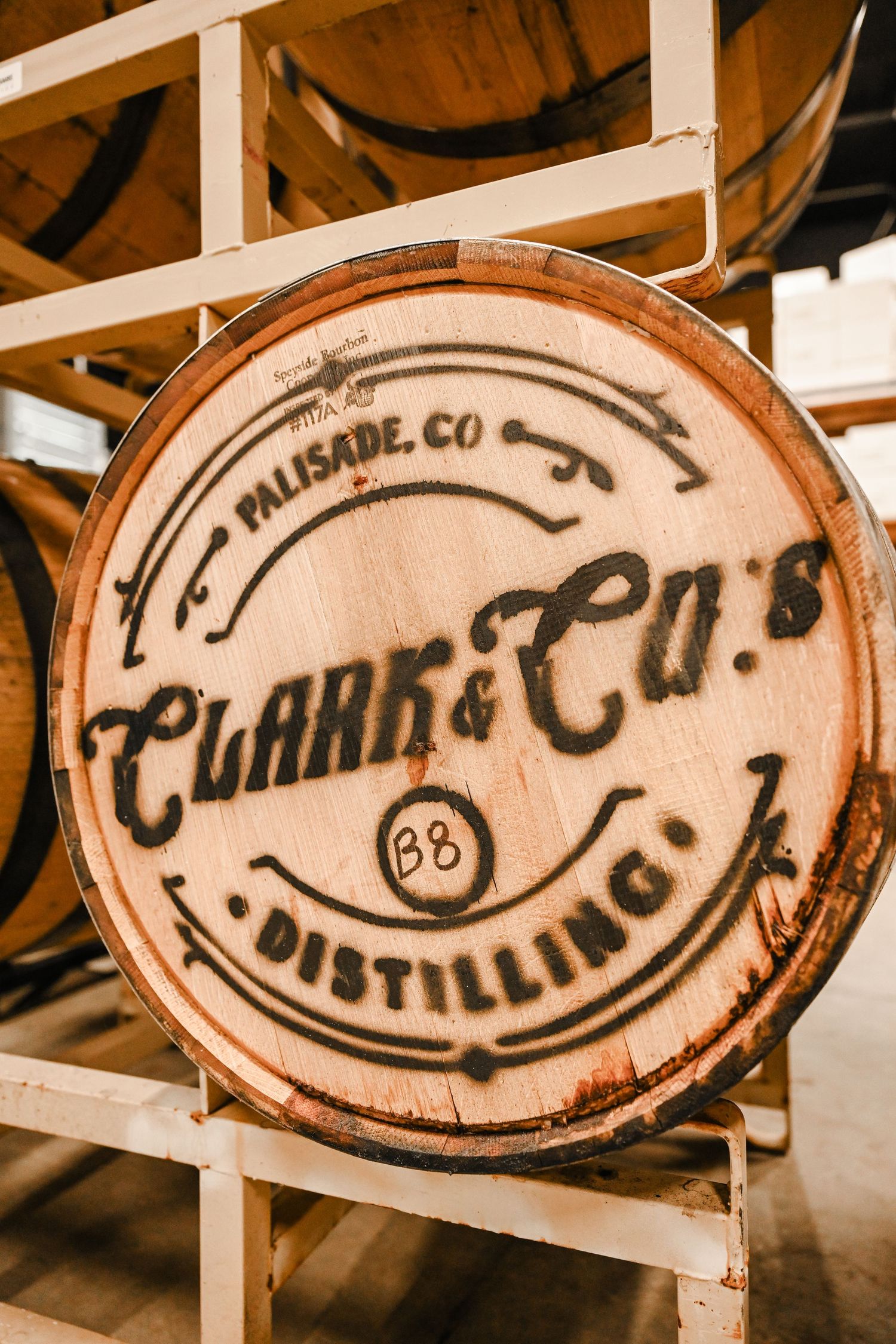 Vintage wooden barrel signs with distillery company branding displayed in sepia tones.