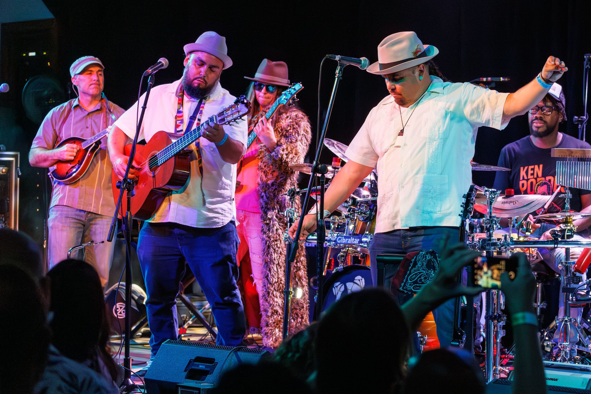 Musicians performing on stage with guitars and instruments during a live concert performance.