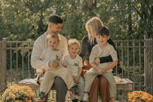 Family in coordinating cream outfits enjoying time together on an outdoor patio at sunset.