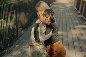 A charming outdoor wedding photoshoot series on a wooden boardwalk shows sweet candid moments between a couple.