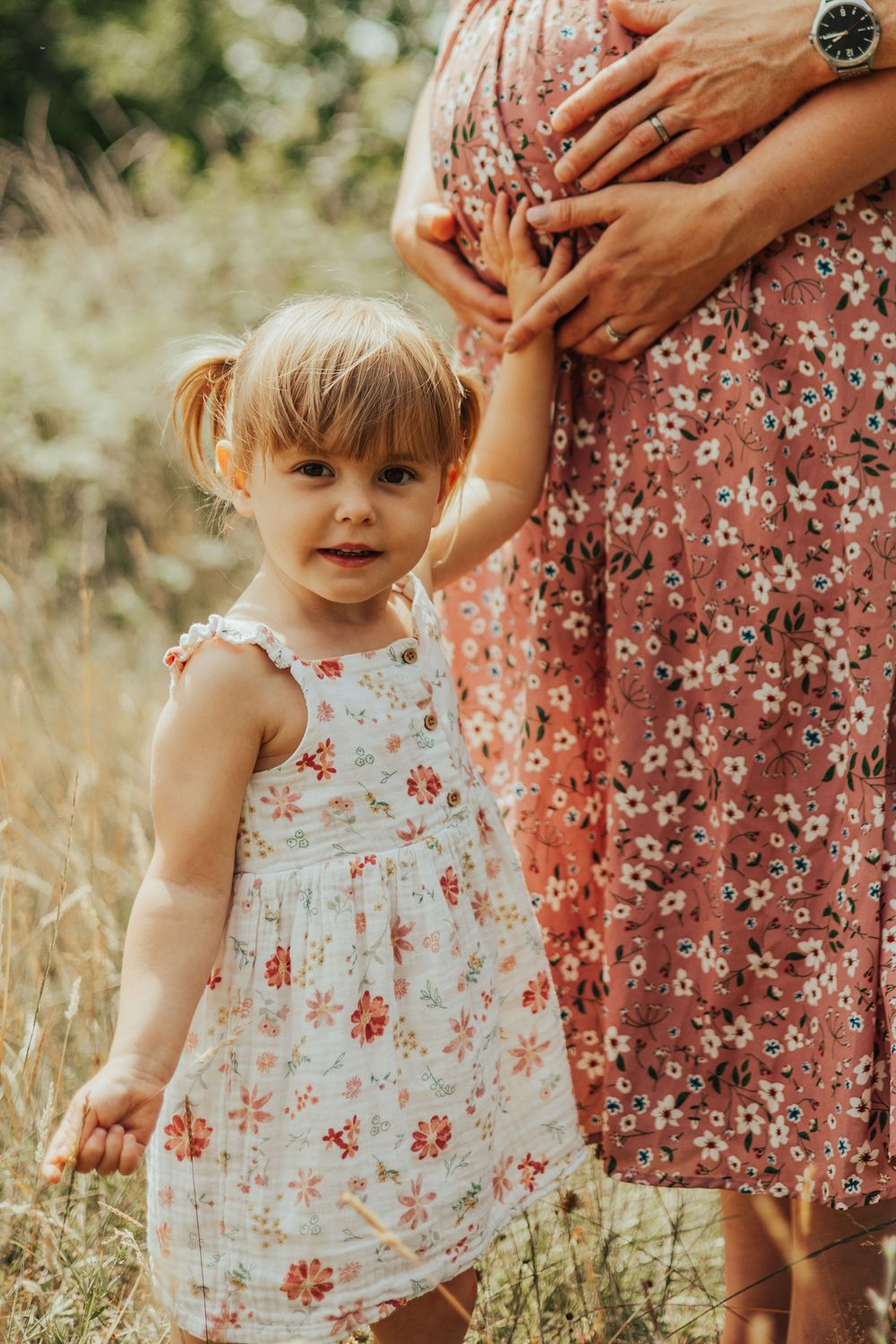 A sweet summer moment in a grassy field showing a matching floral dress on both a small child and an adult.