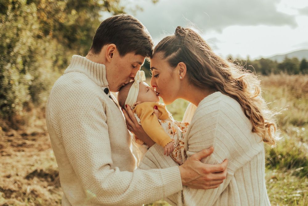 Romantic couple in cream sweaters share intimate moment outdoors in golden autumn field.