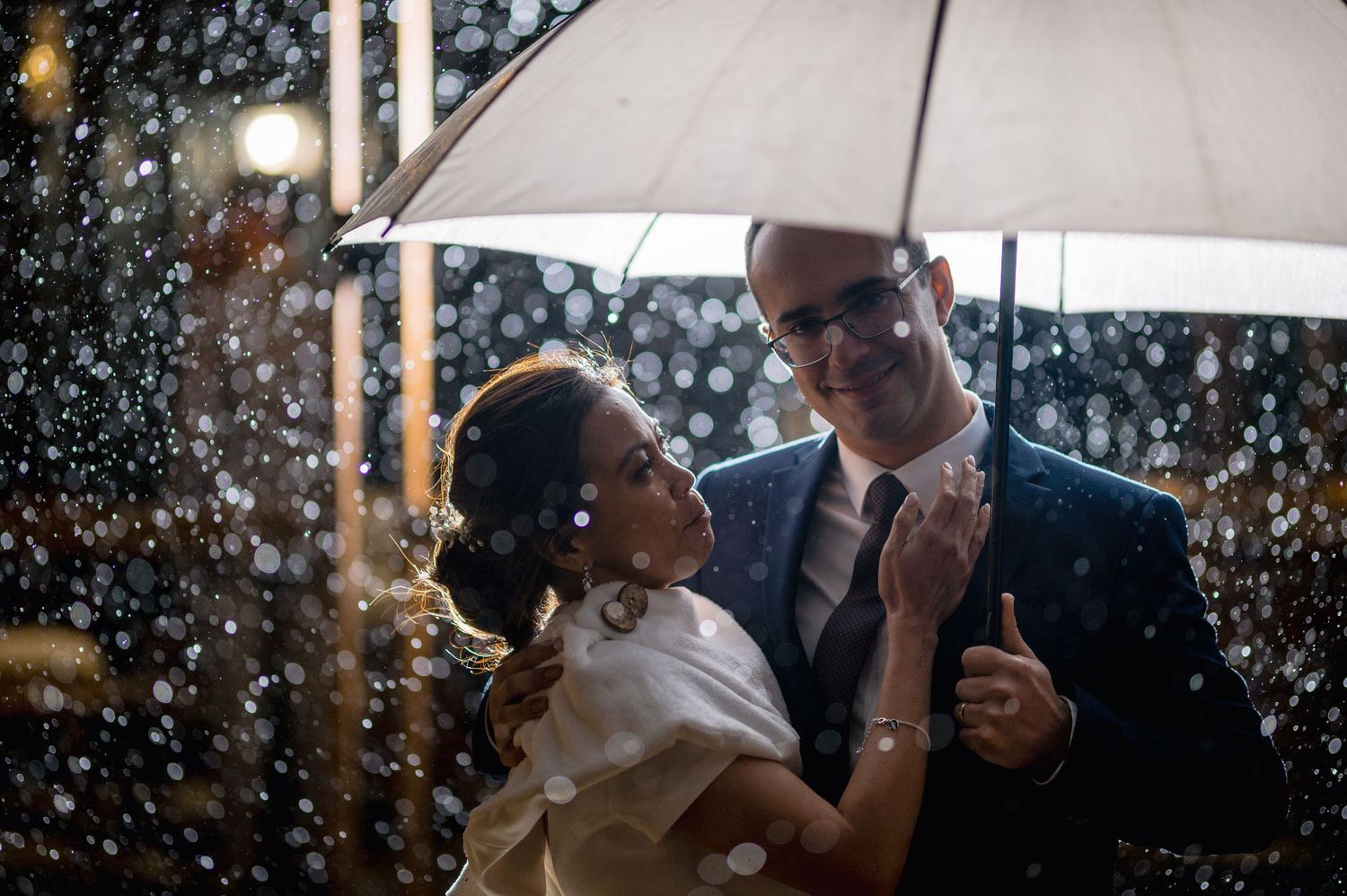 A couple sharing a romantic moment under falling snow at night while dancing.