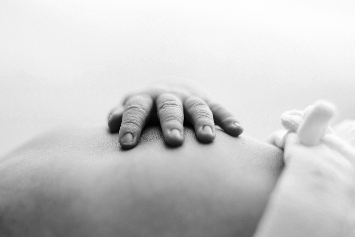 Close-up black and white photo showing close up photo of newborn fingers on belly.