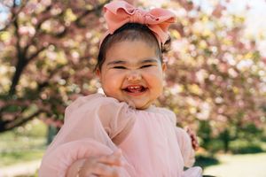 A delightful scene amidst pink cherry blossoms in a spring park, showing joyful expressions and warm laughter.